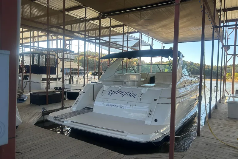 Slide: The Image of 1997 Cruisers 4270 yacht docked in a marina, sheltered under a canopy. - 3