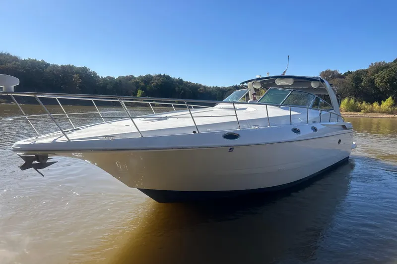 Slide: The Image of 1997 Cruisers 4270 yacht on calm water, surrounded by lush trees under a clear blue sky. - 36