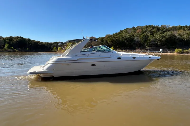 Slide: The Image of 1997 Cruisers 4270 yacht on calm river with forested background under clear blue sky. - 4