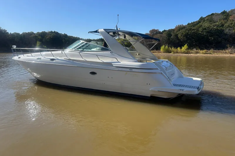 Slide: The Image of 1997 Cruisers 4270 yacht on calm water, surrounded by lush greenery under a clear blue sky. - 40