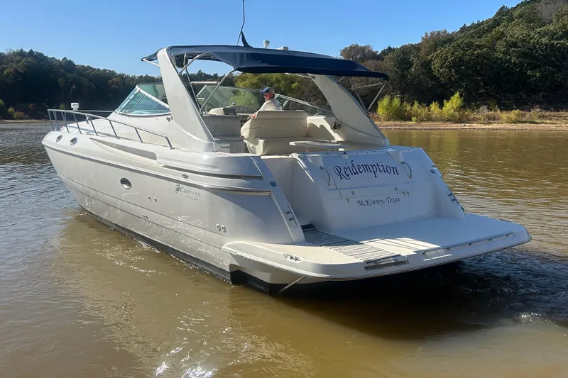 Slide: The Image of 1997 Cruisers 4270 yacht named "Redemption" on calm water near a wooded shoreline. - 43