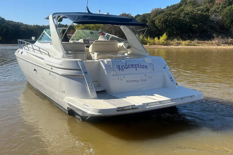 Slide: The Image of 1997 Cruisers 4270 yacht named "Redemption" on a calm lake near a forested shoreline. - 44