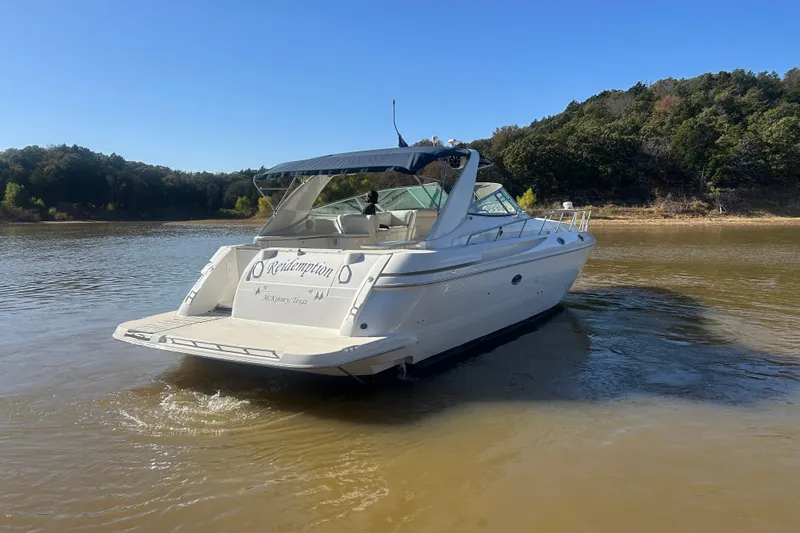 Slide: The Image of 1997 Cruisers 4270 yacht on a calm lake with forested shoreline. - 8