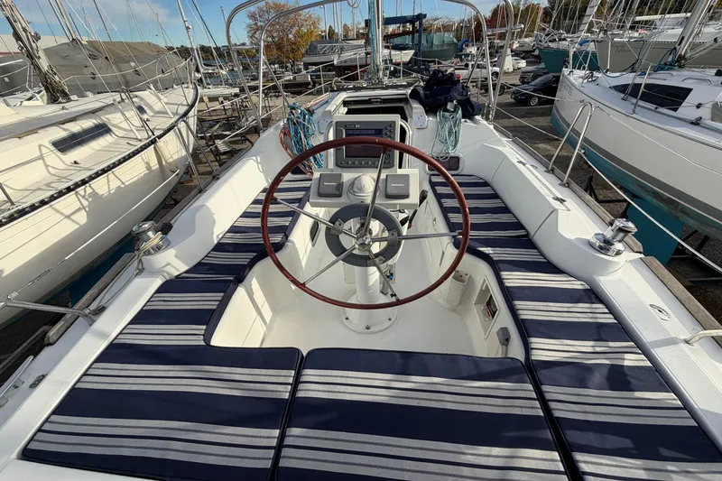 Slide: The Image of 2008 Beneteau 31 sailboat cockpit with striped cushions and steering wheel, docked in a marina. - 30