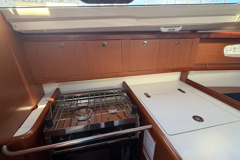 Slide: The Image of 2008 Beneteau 31 yacht kitchen with stove, wooden cabinets, and countertop. - 41