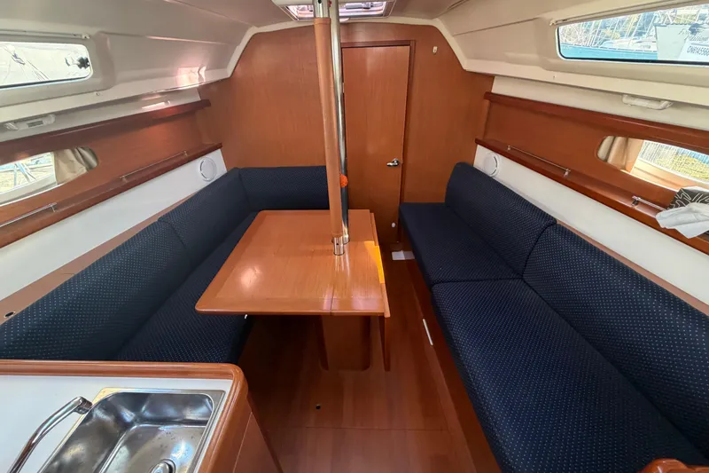 Slide: The Image of Interior of 2008 Beneteau 31 sailboat with wooden table and blue seating. - 42