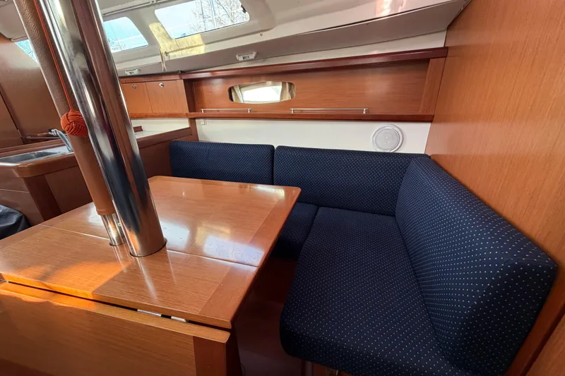 Slide: The Image of Interior of 2008 Beneteau 31 sailboat with wooden table and blue cushioned seating. - 47