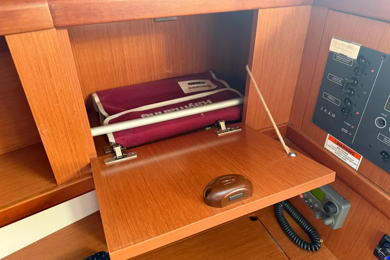 Slide: The Image of Wooden cabinet interior on a 2008 Beneteau 31 sailboat, featuring a maroon life jacket. - 55