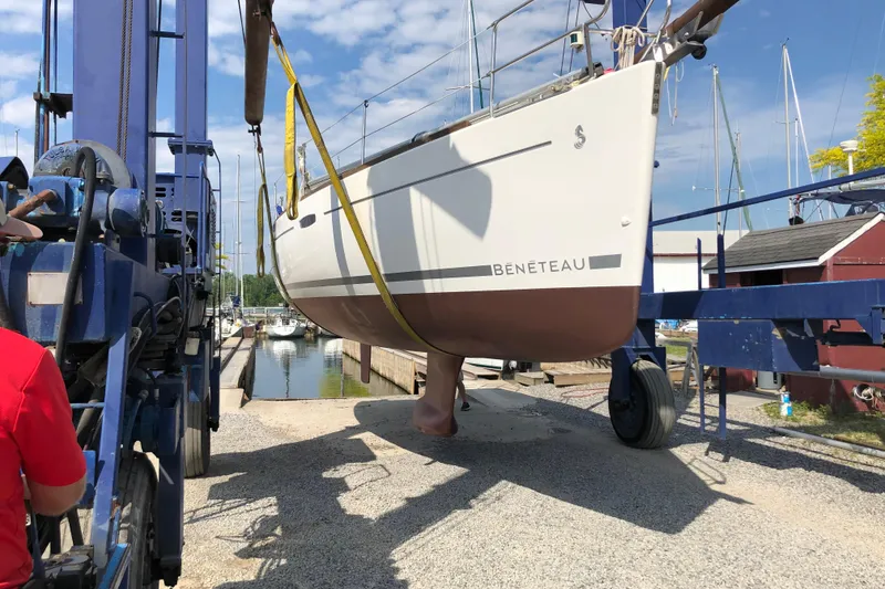 Slide: The Image of 2008 Beneteau 31 sailboat being lifted at a marina with blue sky background. - 77