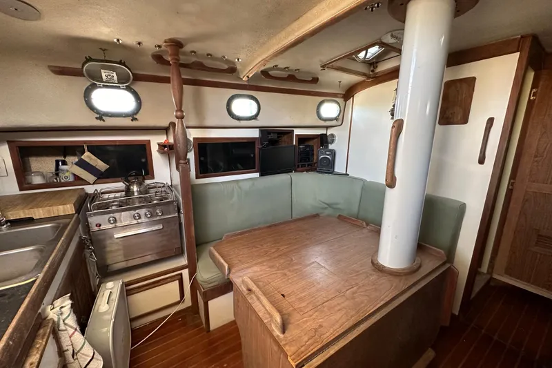 Slide: The Image of 1978 CSY 44 Cutter Rig interior with dining area, stove, and portholes. - 20