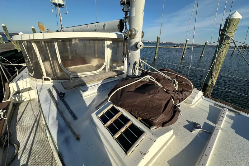 Slide: The Image of 1978 CSY 44 Cutter Rig sailboat deck with covered equipment, docked by the water. - 7