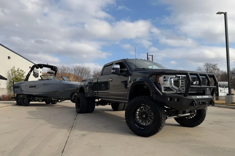 Slide: The Image of Black truck towing a 2026 MB B52 23 Classic boat on a sunny day. - 13