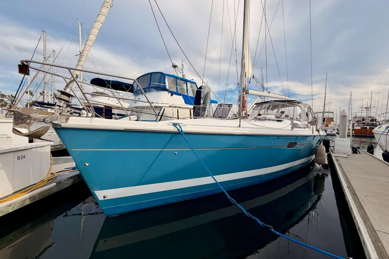 Slide: The Image of 2002 Hunter 460 sailboat docked in marina, featuring a sleek blue hull design. - 2