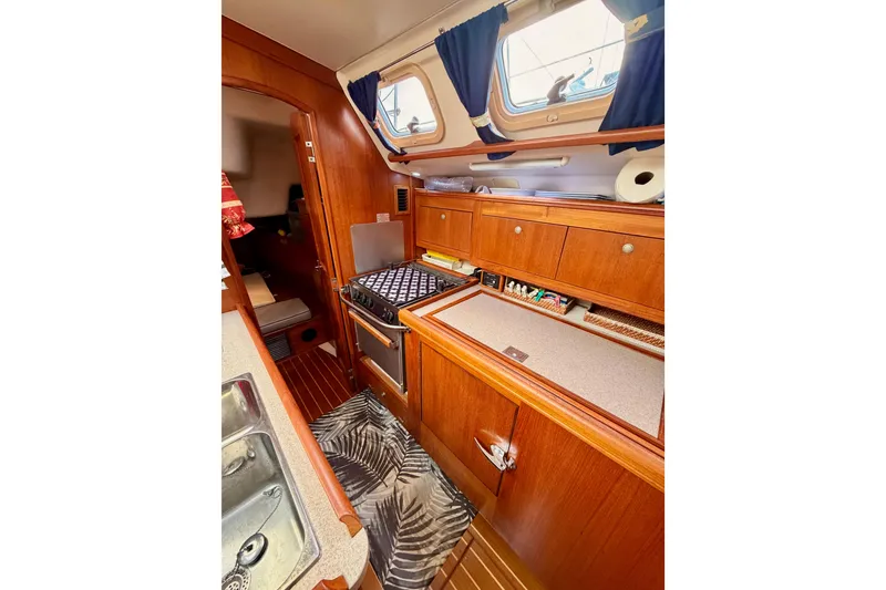 Slide: The Image of Interior of 2002 Hunter 460 sailboat, featuring a compact kitchen with wooden cabinetry and appliances. - 34