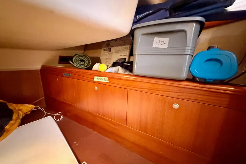Slide: The Image of Interior storage area of a 2002 Hunter 460 sailboat with wooden cabinets and containers. - 39