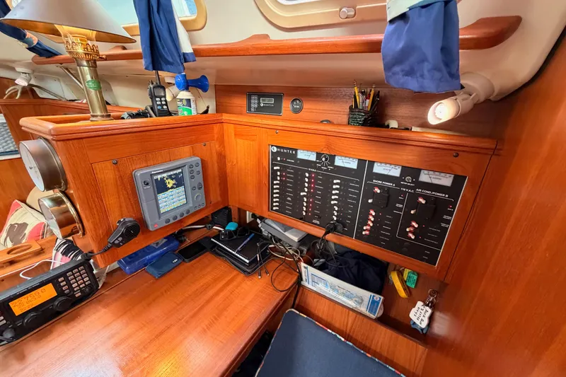 Slide: The Image of 2002 Hunter 460 yacht interior with navigation and control panels, wooden finish, and communication equipment. - 49
