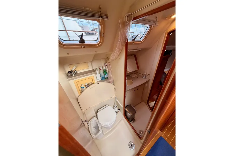Slide: The Image of Bathroom interior of a 2002 Hunter 460 yacht, featuring a toilet, sink, and window. - 54