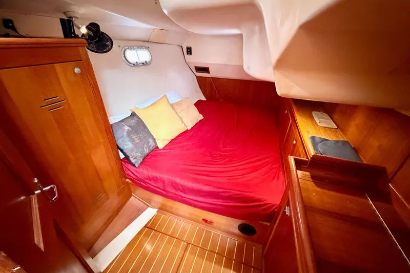 Slide: The Image of Cozy cabin interior of 2002 Hunter 460 yacht with red bedding and wooden furnishings. - 58