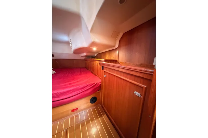 Slide: The Image of Interior cabin of 2002 Hunter 460 yacht with wooden cabinetry and red bedding. - 59