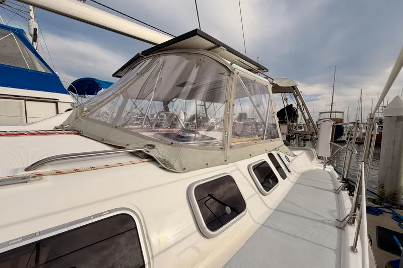 Slide: The Image of 2002 Hunter 460 sailboat docked, featuring a clear cockpit enclosure and sleek design. - 6