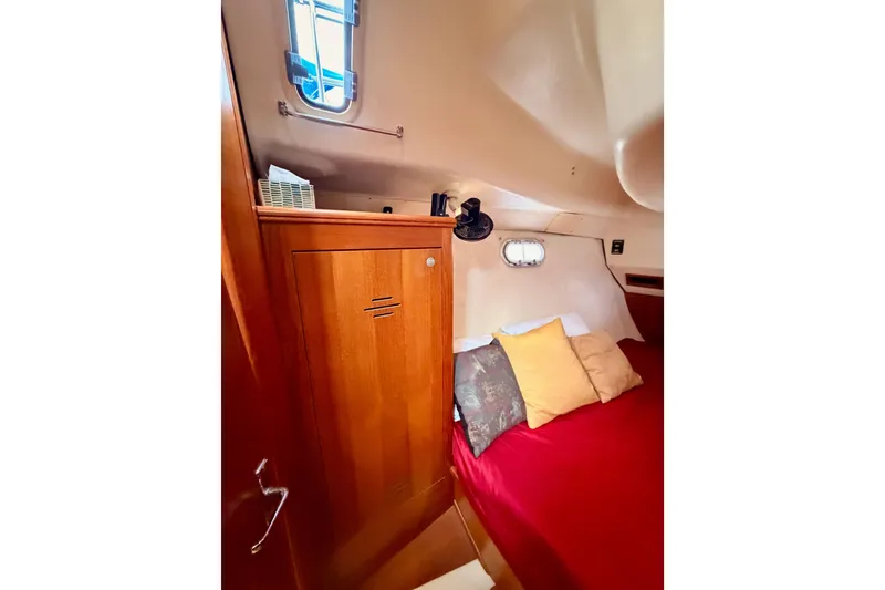 Slide: The Image of Cozy cabin interior of 2002 Hunter 460 sailboat with wooden cabinetry and red bedding. - 60