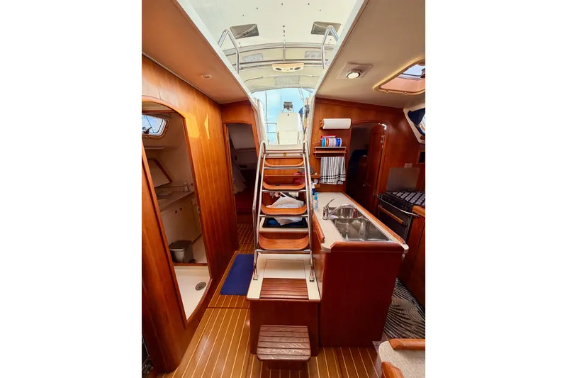 Slide: The Image of Interior of 2002 Hunter 460 sailboat with wooden finish and compact kitchen area. - 80