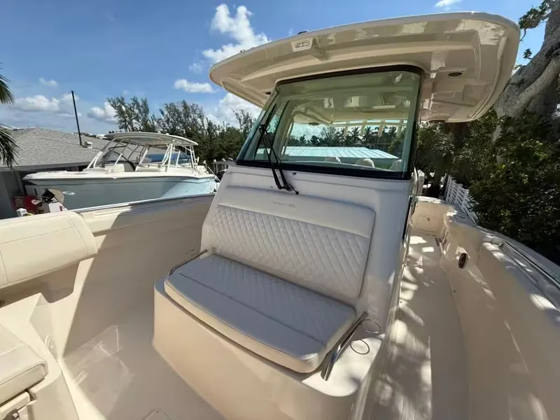 Slide: The Image of 2026 Grady-White Canyon 326 boat interior with cushioned seating under a clear blue sky. - 13