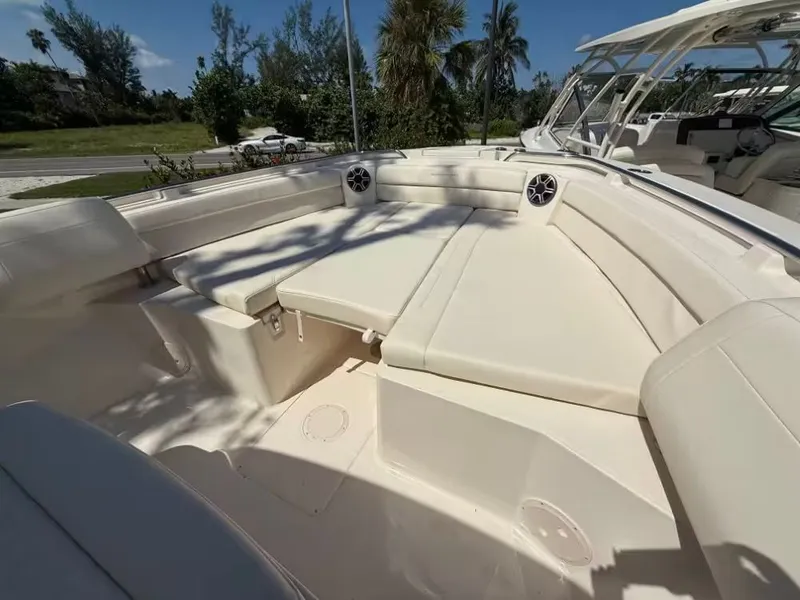 Slide: The Image of 2026 Grady-White Canyon 326 boat interior with cushioned seating and speakers, under clear blue sky. - 9