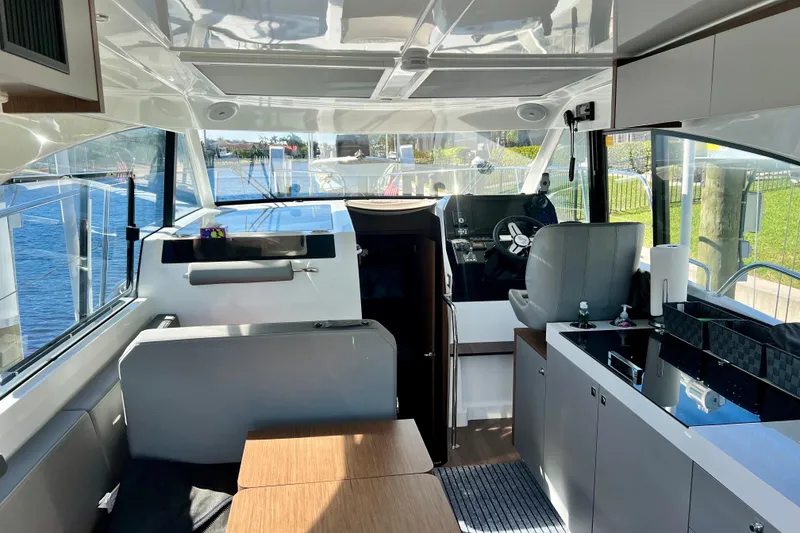 Slide: The Image of Interior of 2024 Beneteau Antares 11, featuring modern helm, seating, and kitchenette with waterfront view. - 11