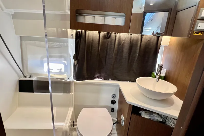 Slide: The Image of 2024 Beneteau Antares 11 bathroom with modern sink, toilet, and wooden cabinetry. - 13