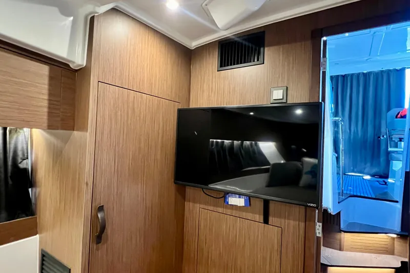 Slide: The Image of Interior of 2024 Beneteau Antares 11 with wood paneling and mounted TV. - 14