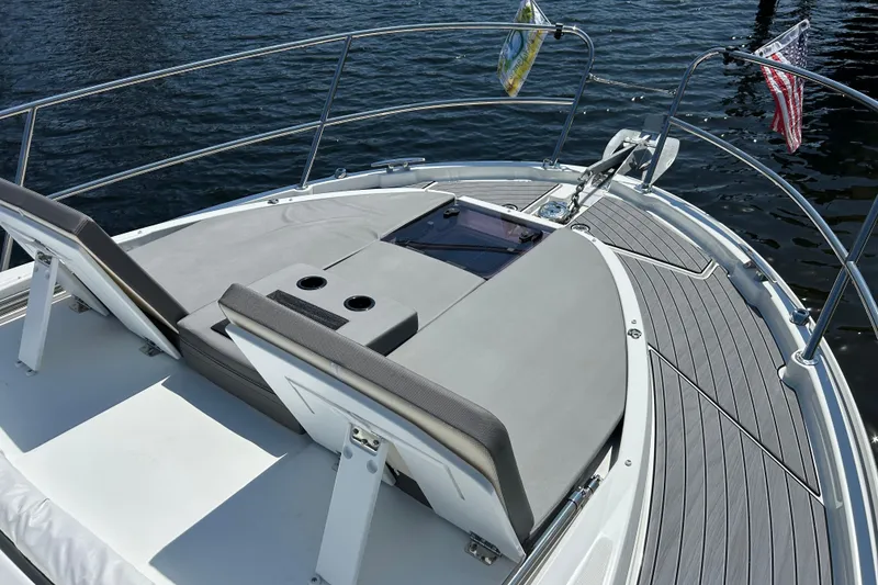 Slide: The Image of 2024 Beneteau Antares 11 boat deck with seating, cup holders, and railing on water. - 17