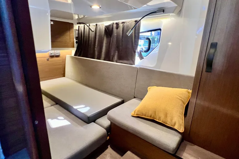 Slide: The Image of 2024 Beneteau Antares 11 interior with cozy seating, window, and yellow cushion. - 20