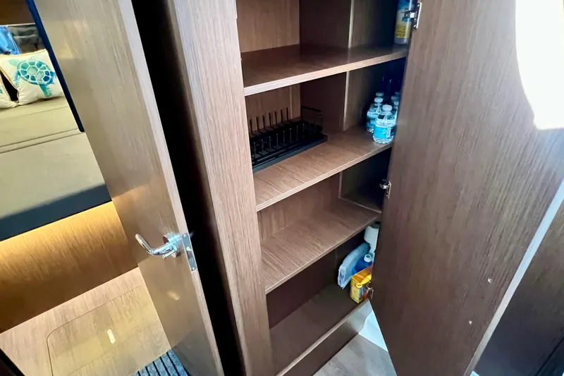 Slide: The Image of 2024 Beneteau Antares 11 interior storage cabinet with shelves and bottled water. - 22