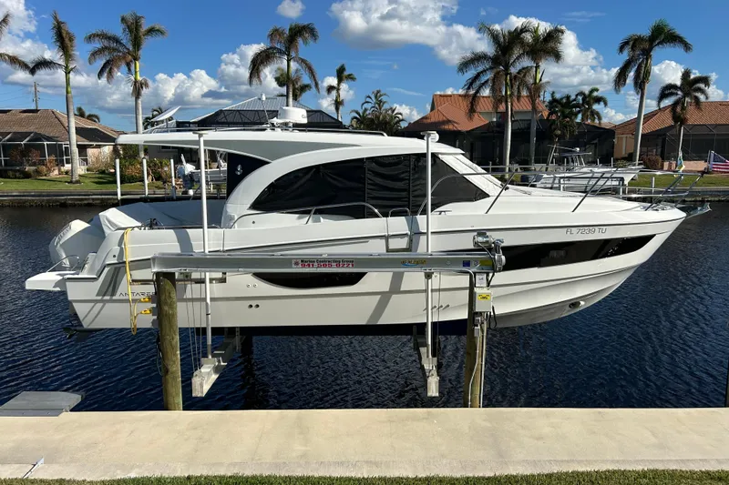 Slide: The Image of 2024 Beneteau Antares 11 boat docked by waterfront homes, under a clear blue sky. - 30