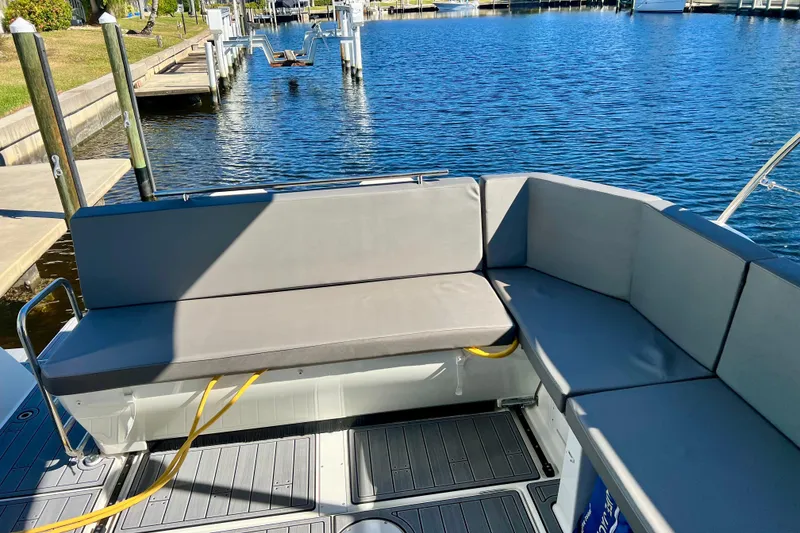 Slide: The Image of 2024 Beneteau Antares 11 boat interior with gray seating, docked by the water. - 5