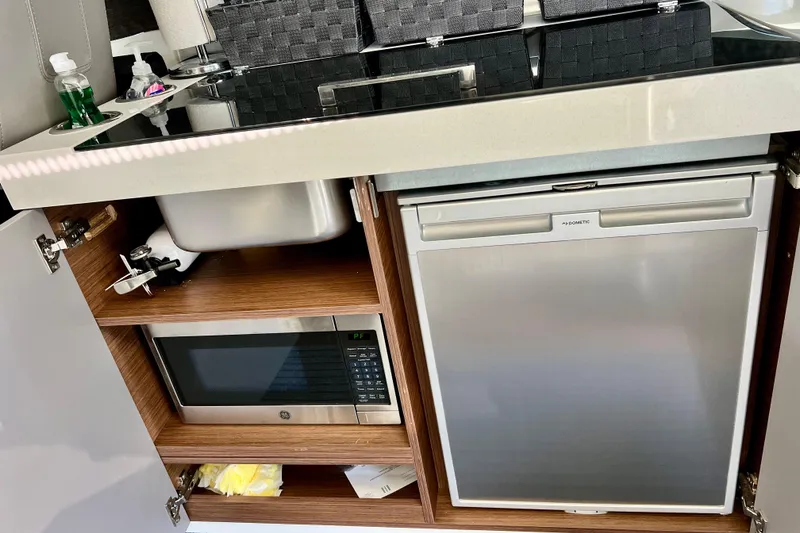 Slide: The Image of 2024 Beneteau Antares 11 kitchen with sink, microwave, and Dometic fridge. - 9