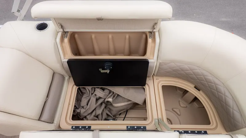 Slide: The Image of 2019 Sun Tracker 24 Party Barge storage compartments with beige seating and cup holder. - 10