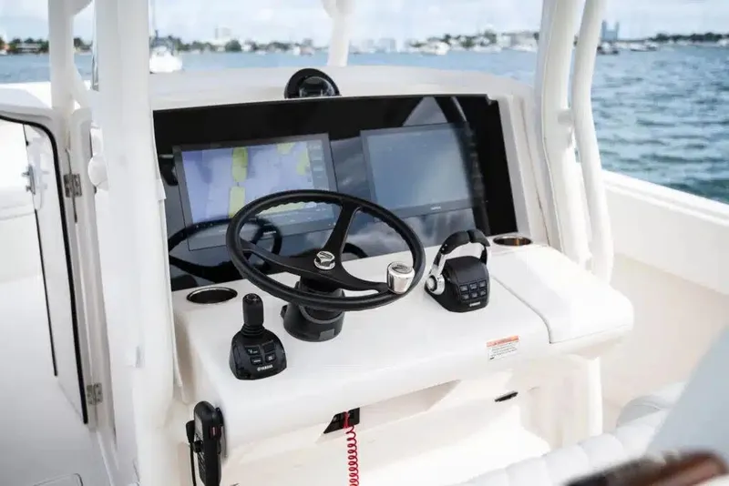 Slide: The Image of 2019 Jupiter 34 HFS boat helm with steering wheel, navigation screens, and controls on open water. - 6
