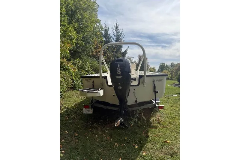 Slide: The Image of 2020 Boston Whaler 190 Montauk boat on trailer, parked on grass with trees in background. - 2