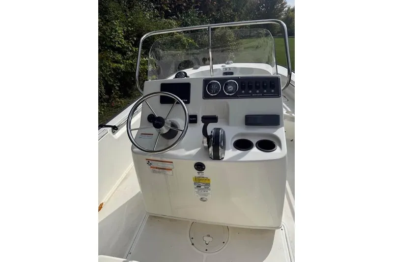 Slide: The Image of 2020 Boston Whaler 190 Montauk boat on trailer, parked on grass near wooden structure. - 3