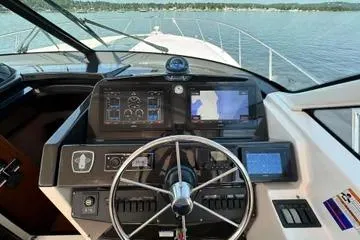 Slide: The Image of 2019 Tiara Yachts 4300 Open helm with navigation screens and steering wheel on calm water. - 9