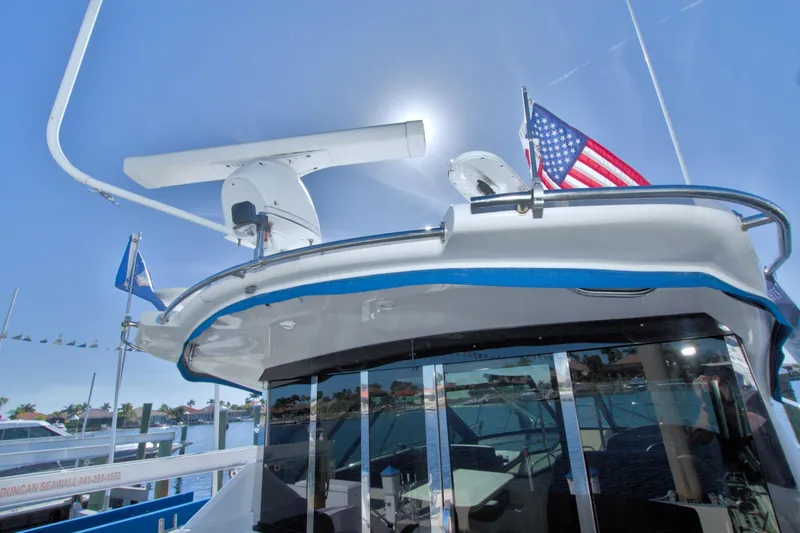 Slide: The Image of 2014 Regal 46 Sport Coupe yacht with flags, docked under clear blue sky. - 13