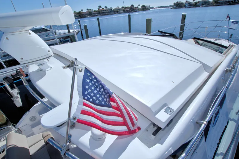 Slide: The Image of 2014 Regal 46 Sport Coupe yacht with American flag, docked by the water. - 14