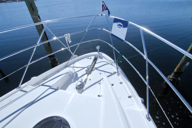 Slide: The Image of 2014 Regal 46 Sport Coupe yacht bow with flags on calm water. - 17