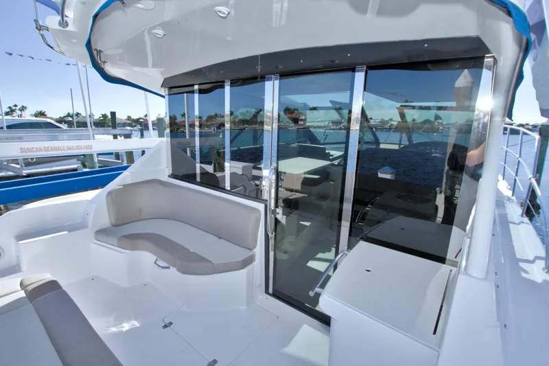 Slide: The Image of 2014 Regal 46 Sport Coupe yacht with sleek seating and glass doors at a marina. - 23