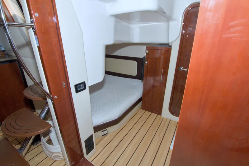 Slide: The Image of 2014 Regal 46 Sport Coupe cabin interior with wooden finishes and compact bed. - 53
