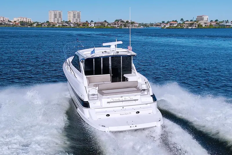 Slide: The Image of 2014 Regal 46 Sport Coupe cruising on a scenic waterway with city skyline backdrop. - 8