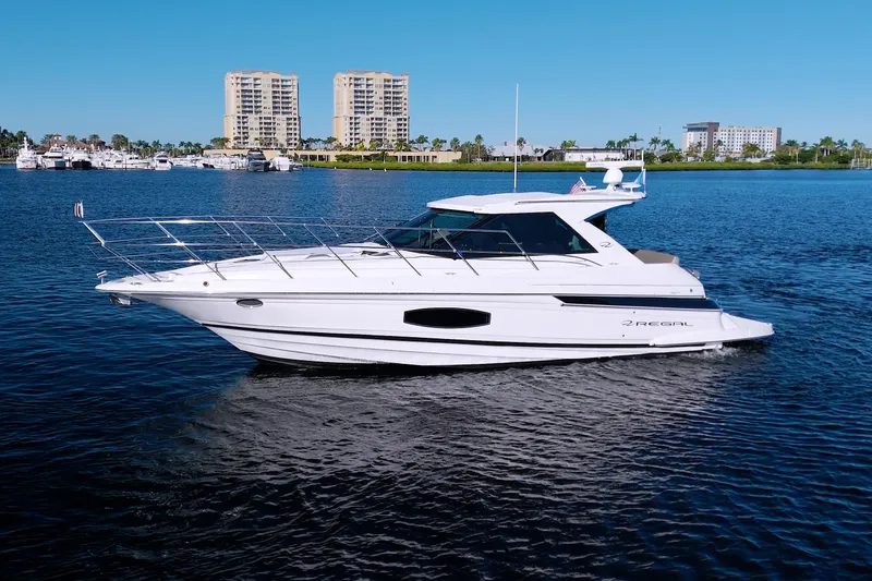 Slide: The Image of 2014 Regal 46 Sport Coupe yacht cruising on a sunny day with cityscape background. - 84