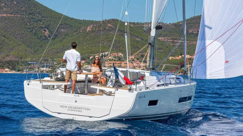 Slide: The Image of 2025 Hanse 410 sailboat cruising on blue waters with scenic mountain backdrop. - 7